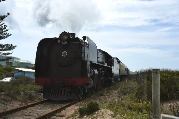 A steam train heads towards the camera, it is only a few metres away. It will exit to the left of the frame.