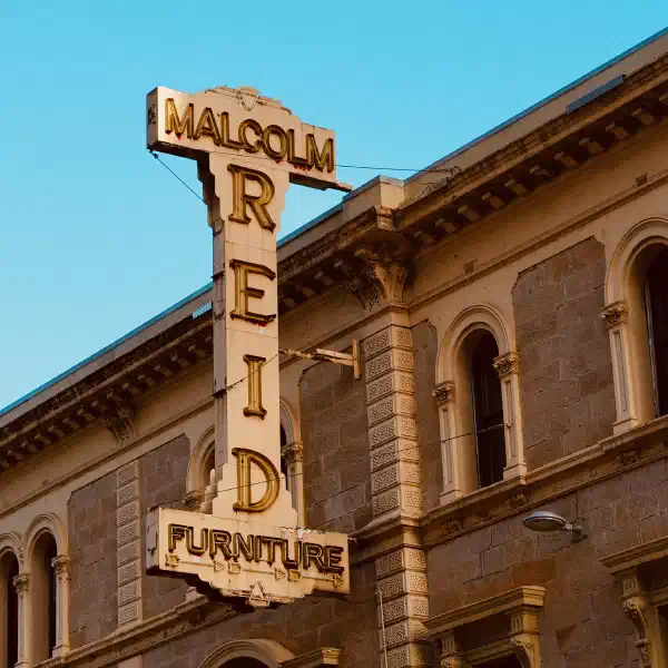 Large, old sign on the side of a building for 'Malcolm Reid Furniture'