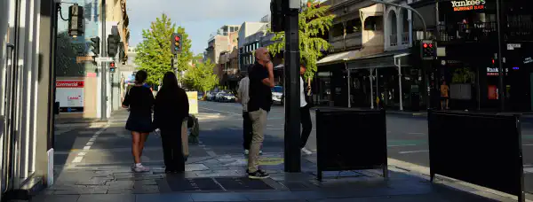 A street intersection. Several people are waiting to cross the road.