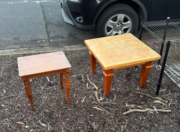 two wooden tables, sitting on the verge at the side of the road