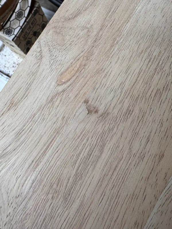 Close-up of the tabletop, showing a gouge in the wood